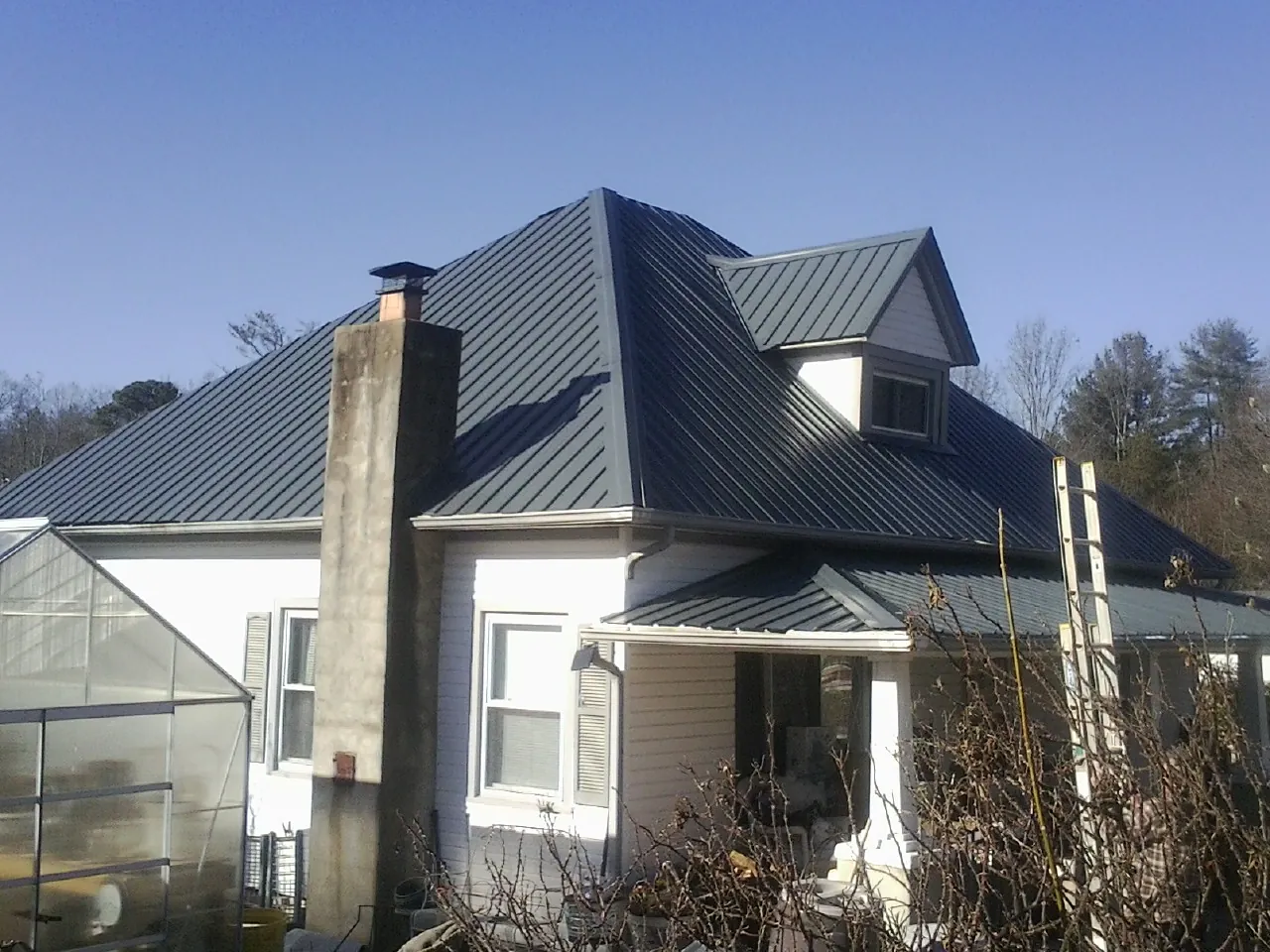Dark blue standing seam metal roof on a white farmhouse with dormer — Slate & Tile Roof Repair by Roofing Brothers in Moundsville