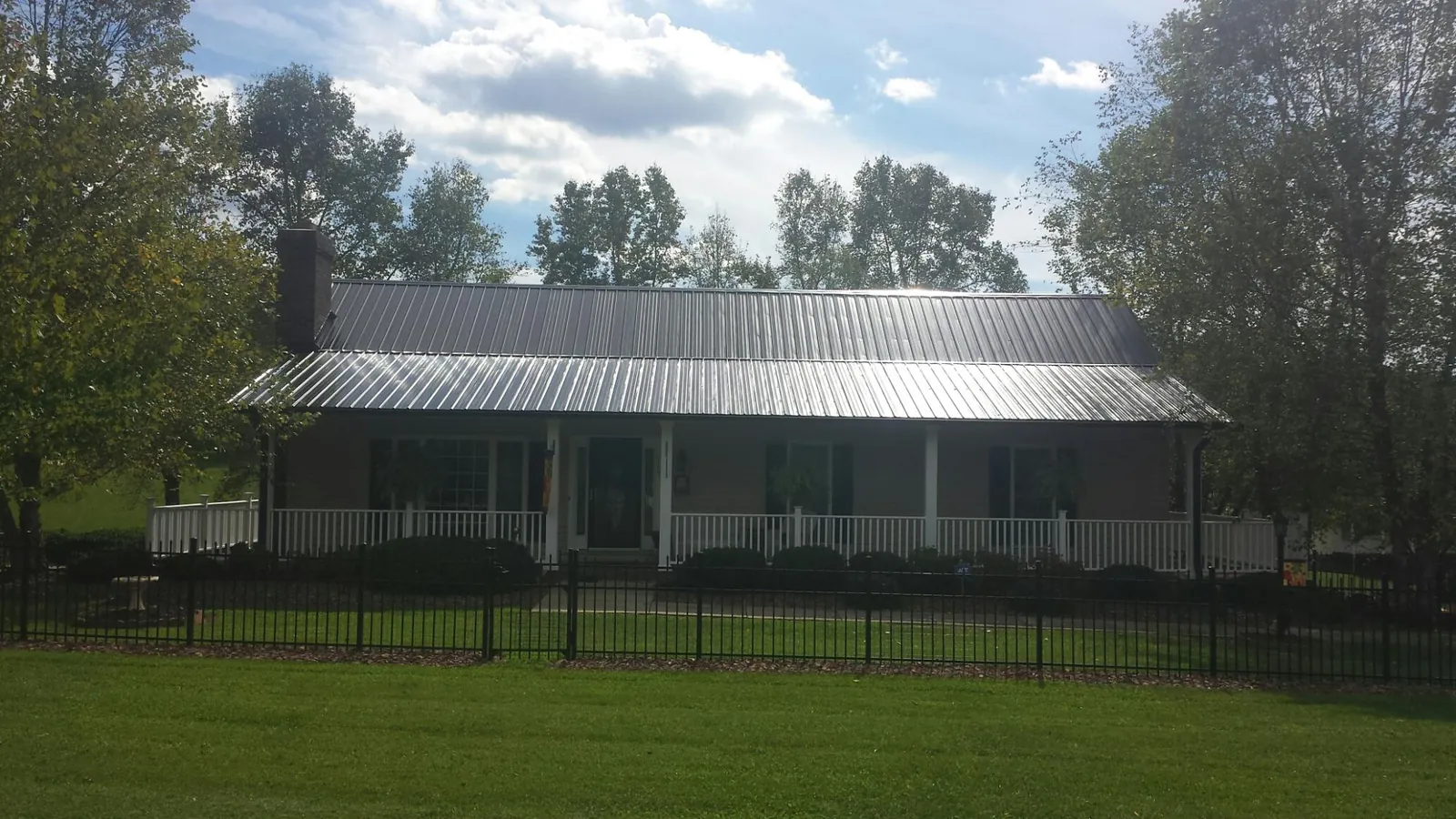 Gray metal roof on a brick ranch with a full width front porch — Gutter Guard Installation work by our crew in Moundsville