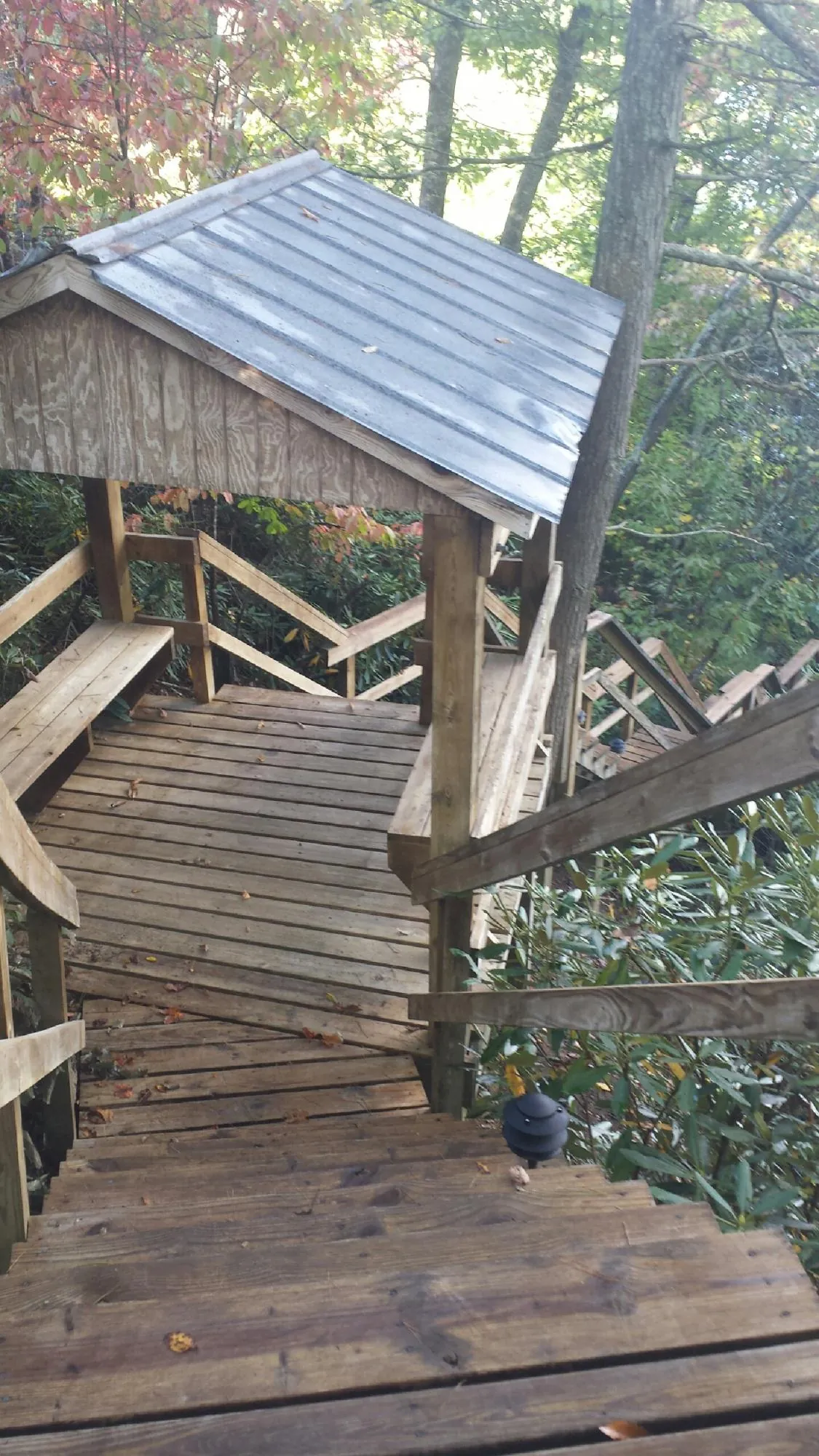 Metal roofed shelter over wooden steps on a wooded walkway — Skylight Repair & Installation work by our crew in Moundsville