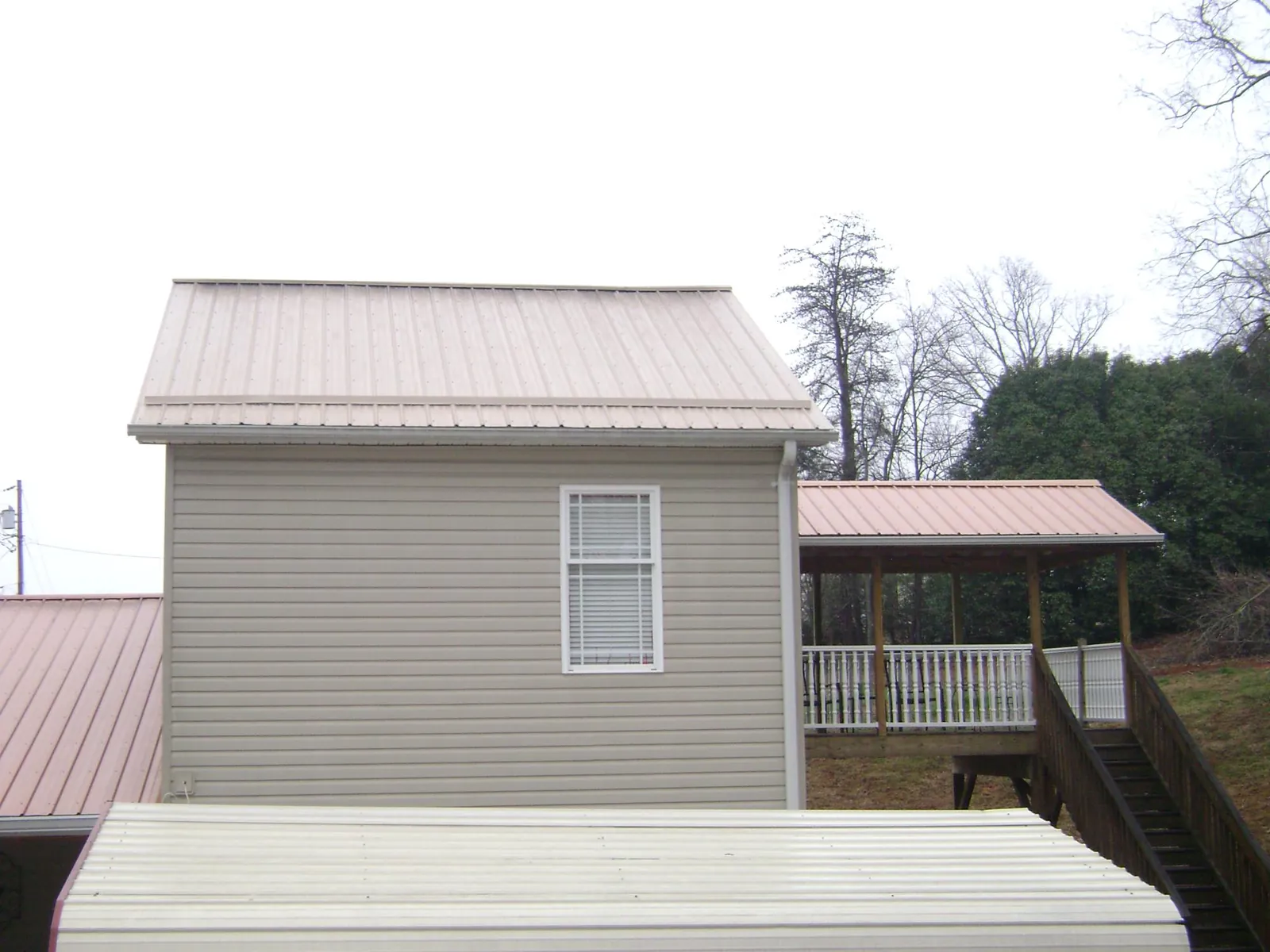 Tan metal roofs on a two story addition and attached porch, from a Roof Replacement job in Moundsville