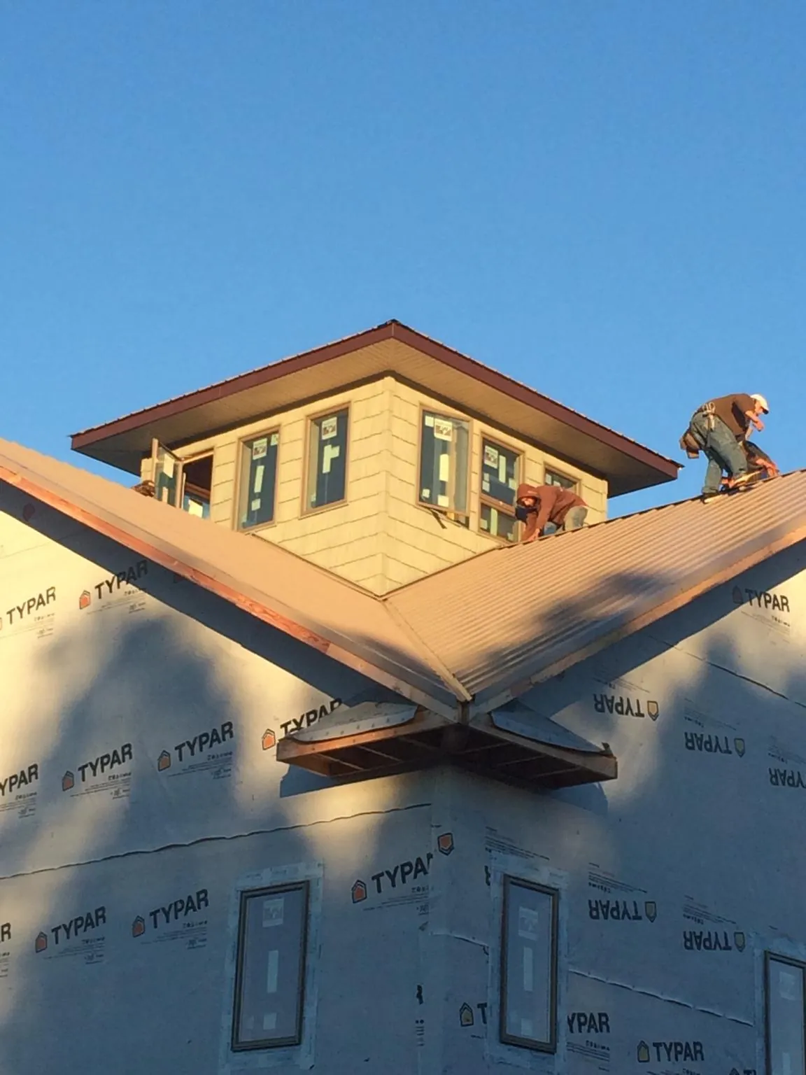 Roofers working around a rooftop cupola on a new metal roof at sunset — Roof Waterproofing in Moundsville by Roofing Brothers